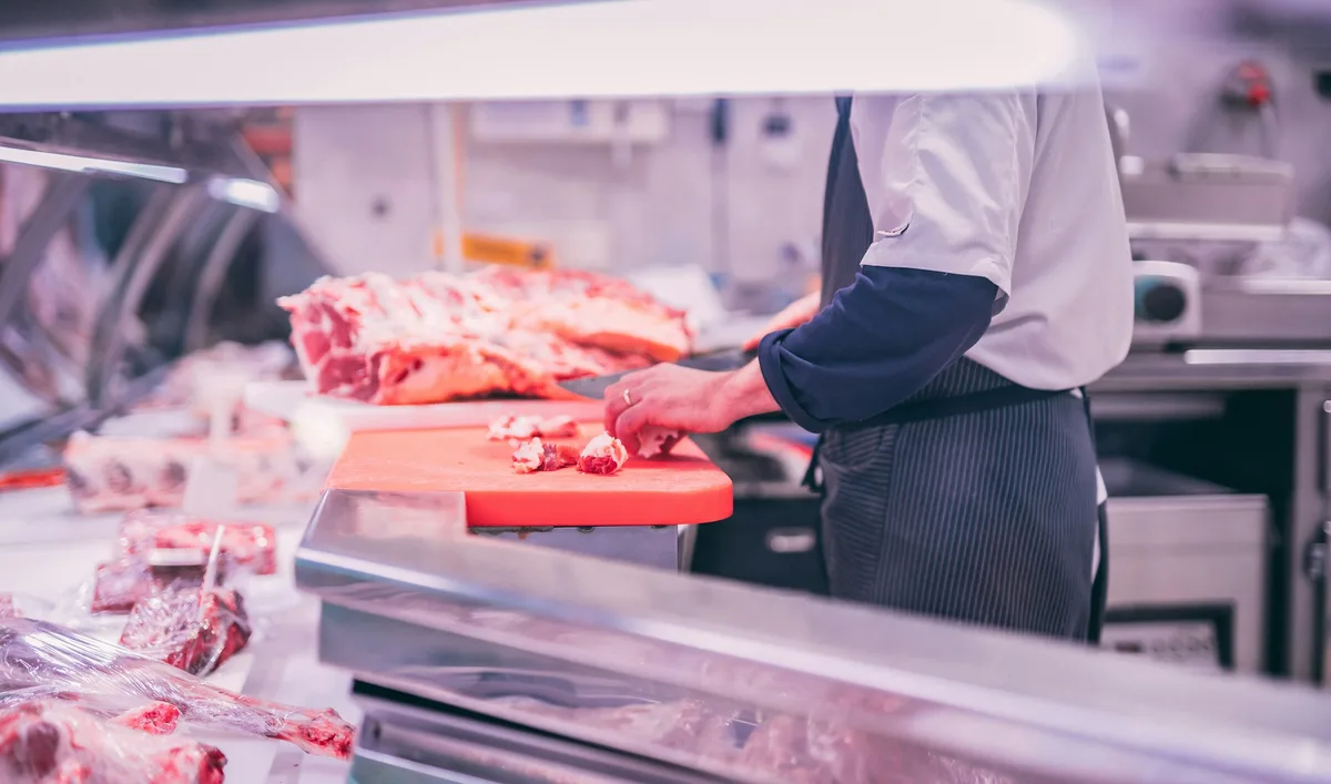 man slicing raw meat — professional food preparation environment